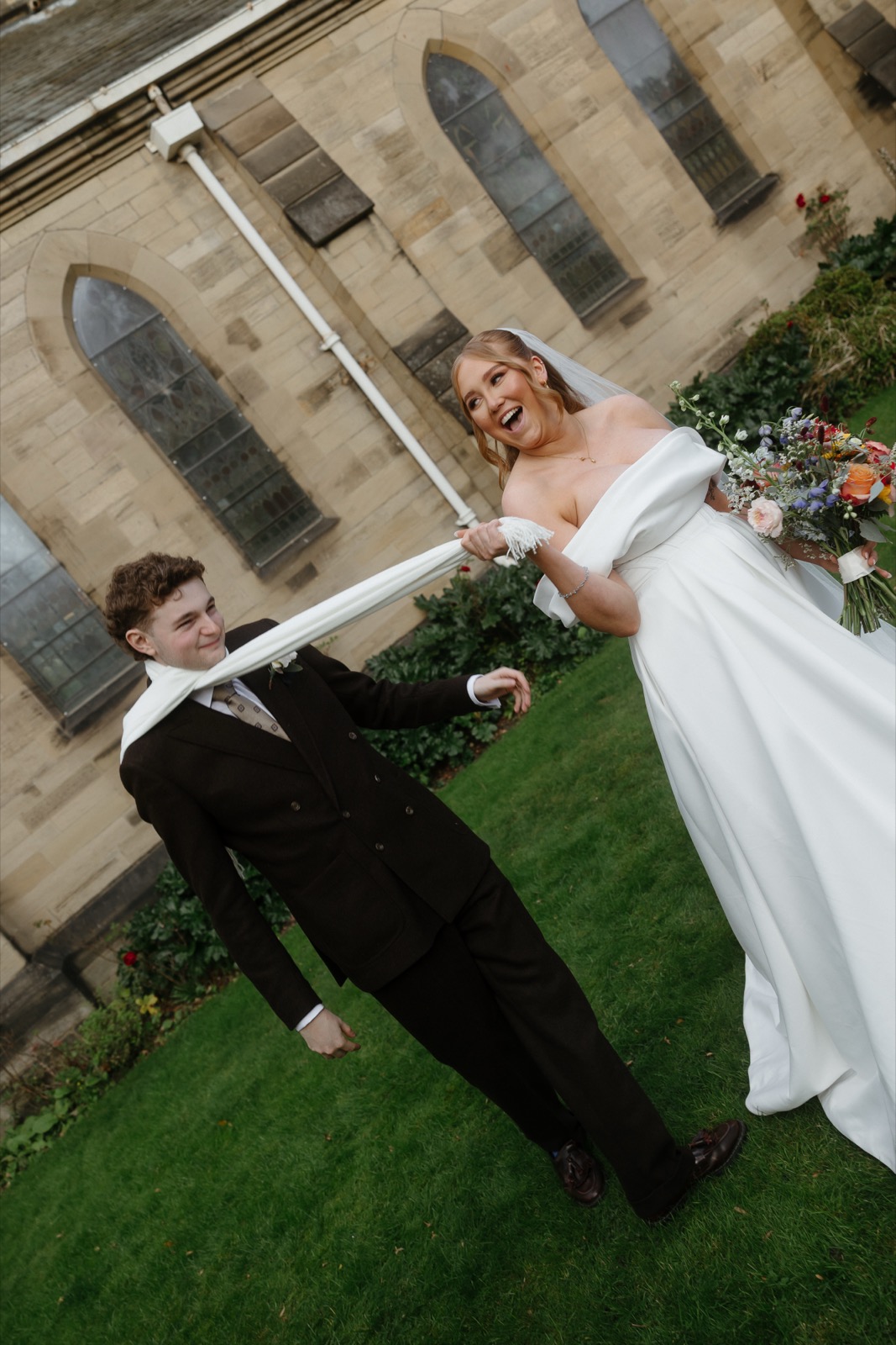 Newlyweds laughing outside a stone church